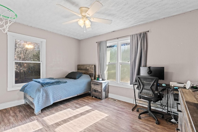 bedroom featuring hardwood / wood-style floors, a textured ceiling, and ceiling fan