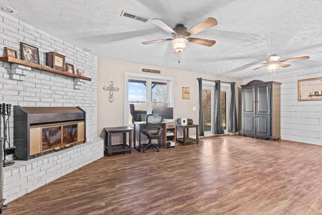 office space with hardwood / wood-style floors, a textured ceiling, and a brick fireplace