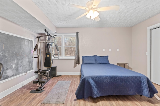 bedroom with a textured ceiling, light hardwood / wood-style floors, and ceiling fan