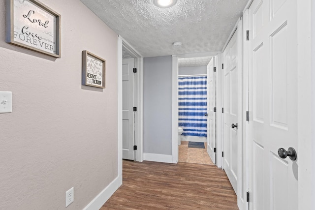 hall featuring wood-type flooring and a textured ceiling