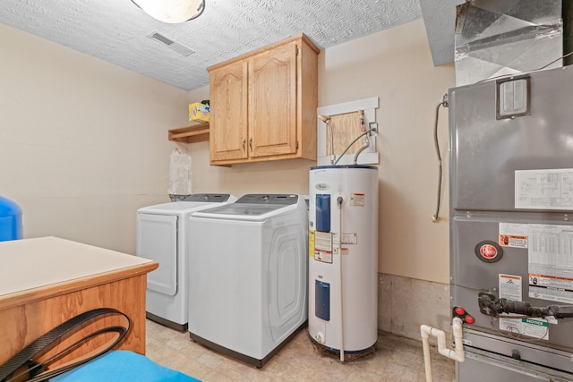 clothes washing area with cabinets, a textured ceiling, electric water heater, heating unit, and washing machine and clothes dryer