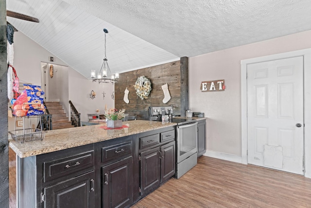 kitchen featuring hanging light fixtures, light hardwood / wood-style flooring, a textured ceiling, vaulted ceiling, and electric stove