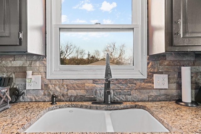 details with decorative backsplash, light stone counters, and sink