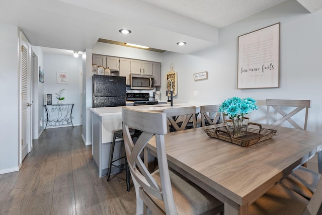 dining room with a textured ceiling, sink, and dark wood-type flooring