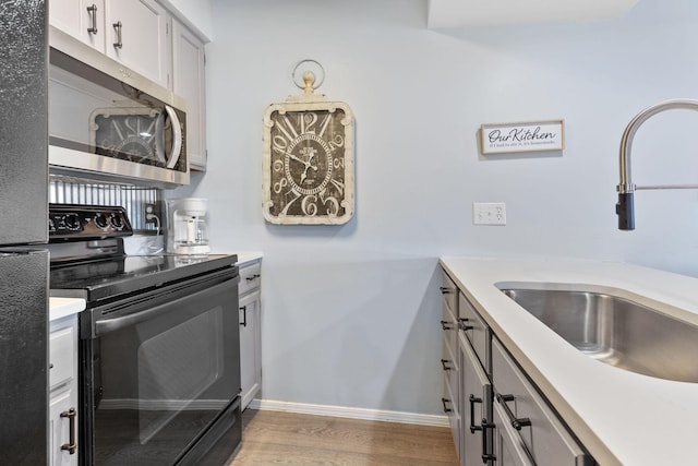 kitchen featuring black electric range, light hardwood / wood-style floors, and sink