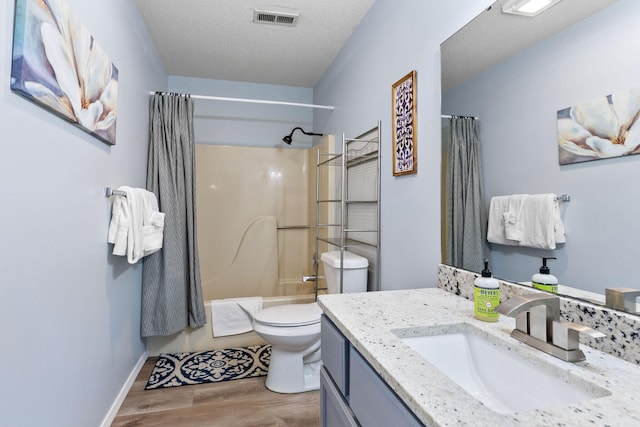 full bathroom featuring hardwood / wood-style floors, a textured ceiling, toilet, shower / tub combo with curtain, and vanity