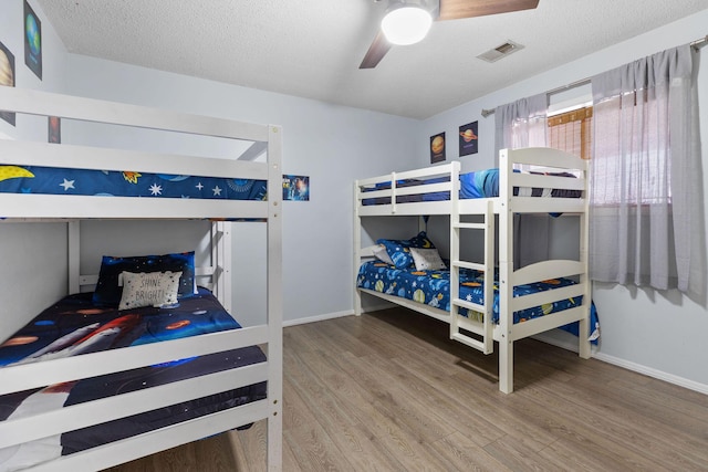 bedroom featuring hardwood / wood-style floors, a textured ceiling, and ceiling fan