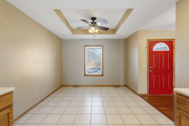 entrance foyer with a tray ceiling, light hardwood / wood-style flooring, and ceiling fan