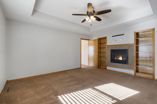 unfurnished living room with a raised ceiling, ceiling fan, carpet, and a textured ceiling