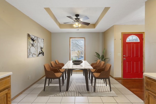 dining space featuring ceiling fan, a raised ceiling, and light wood-type flooring