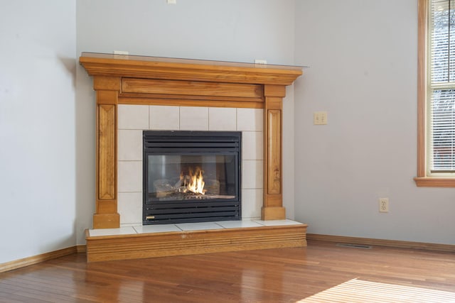 room details featuring wood-type flooring and a tiled fireplace