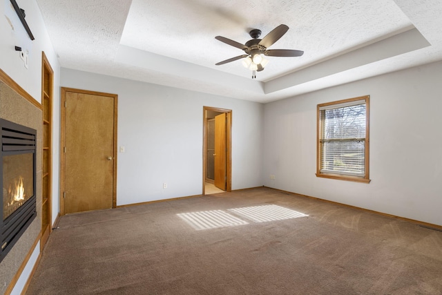 unfurnished bedroom featuring light carpet, ceiling fan, a textured ceiling, connected bathroom, and a tray ceiling