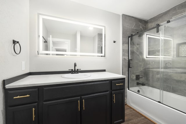 bathroom featuring hardwood / wood-style flooring, vanity, and shower / bath combination with glass door