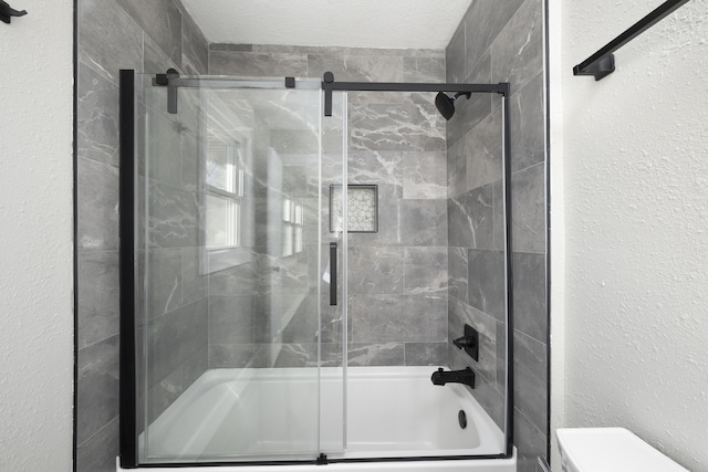 bathroom featuring shower / bath combination with glass door, a textured ceiling, and toilet