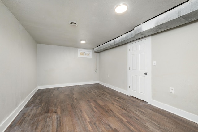 basement featuring a textured ceiling and dark hardwood / wood-style floors