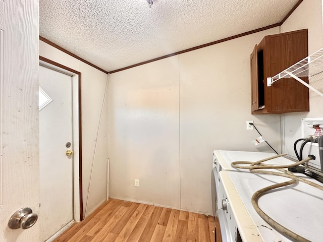 laundry room with light hardwood / wood-style floors, ornamental molding, a textured ceiling, and washer / clothes dryer