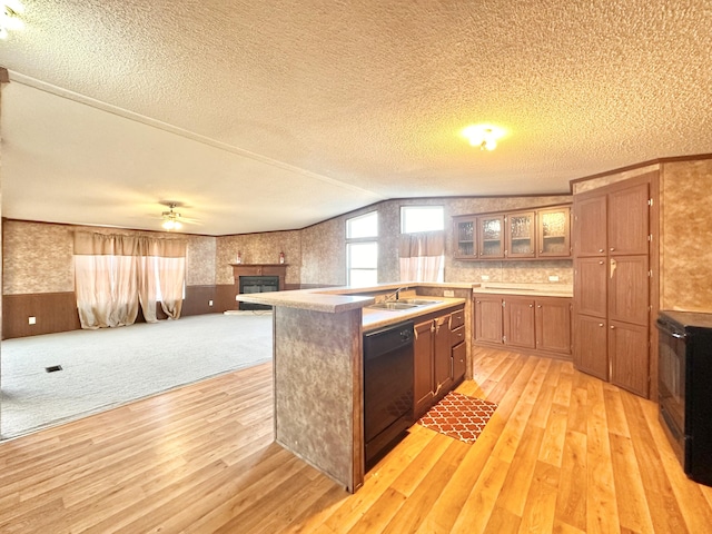 kitchen featuring a kitchen island with sink, black appliances, vaulted ceiling, light hardwood / wood-style flooring, and a textured ceiling