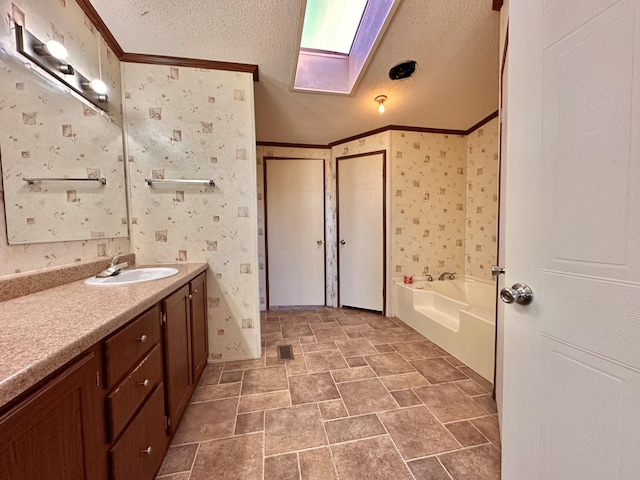 bathroom featuring a bathing tub, vanity, a textured ceiling, and crown molding