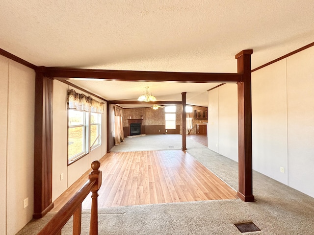 unfurnished living room featuring a textured ceiling, light hardwood / wood-style floors, lofted ceiling, and ornamental molding