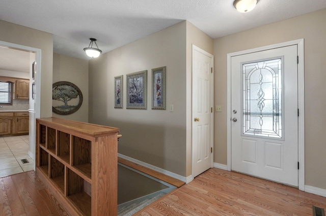 foyer with light wood-type flooring and a textured ceiling