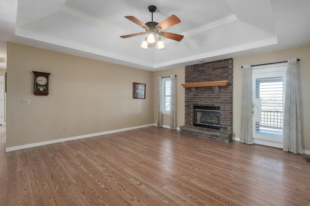 10071 W Farm Road 48, Walnut Grove, MO 65770 - unfurnished living room featuring a tray ceiling, wood finished floors, ceiling fan, and a brick fireplace