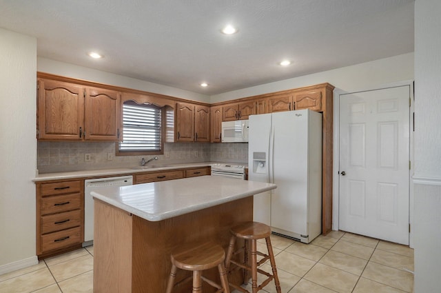 kitchen with light tile patterned flooring, white appliances, a kitchen breakfast bar, decorative backsplash, and a kitchen island