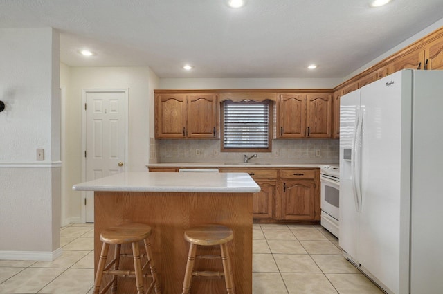 kitchen with a center island, sink, tasteful backsplash, white appliances, and a kitchen bar