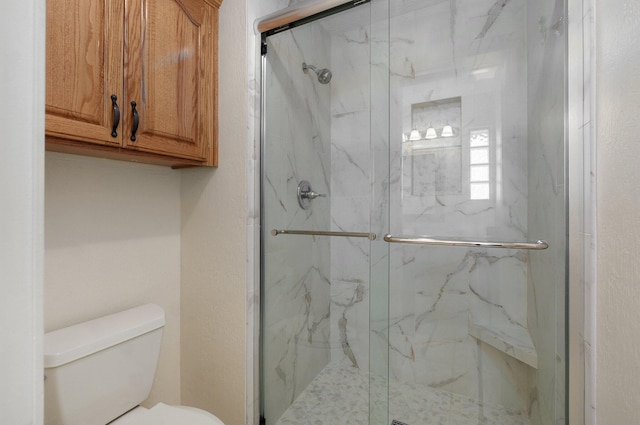 bathroom featuring toilet and a shower with door