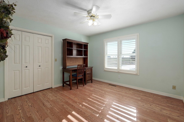 home office featuring ceiling fan, light hardwood / wood-style floors, and a textured ceiling