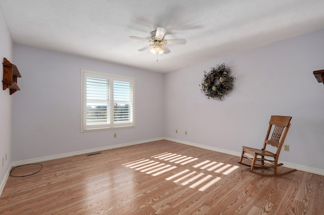 empty room with a textured ceiling, light hardwood / wood-style flooring, and ceiling fan