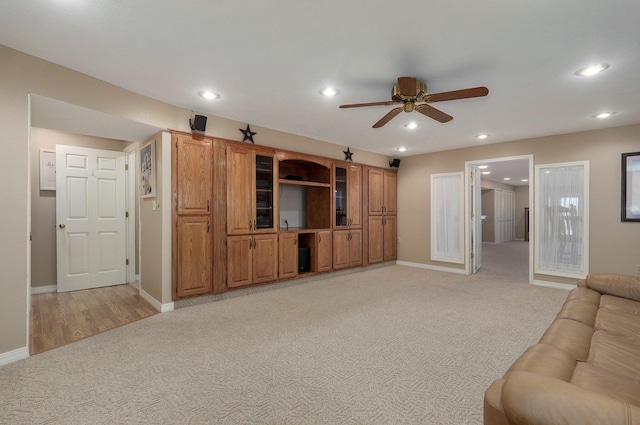 unfurnished living room featuring light colored carpet and ceiling fan