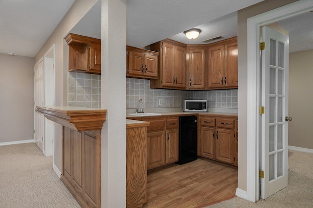 10071 W Farm Road 48, Walnut Grove, MO 65770 - kitchen featuring stainless steel microwave, light countertops, brown cabinets, tasteful backsplash, and light colored carpet