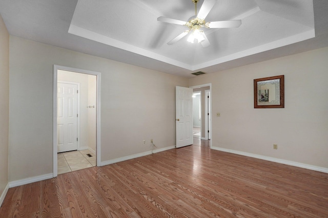 spare room featuring light hardwood / wood-style floors, a raised ceiling, and ceiling fan