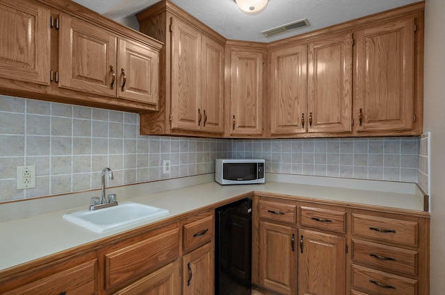 kitchen featuring black refrigerator, decorative backsplash, sink, and a textured ceiling