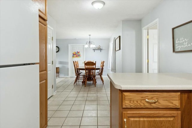 kitchen with an inviting chandelier, pendant lighting, light tile patterned floors, and white refrigerator