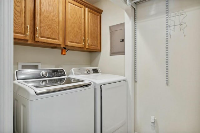 clothes washing area with washer and dryer, electric panel, and cabinets