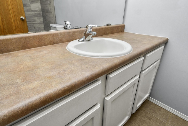 bathroom with toilet, vanity, and tile patterned floors