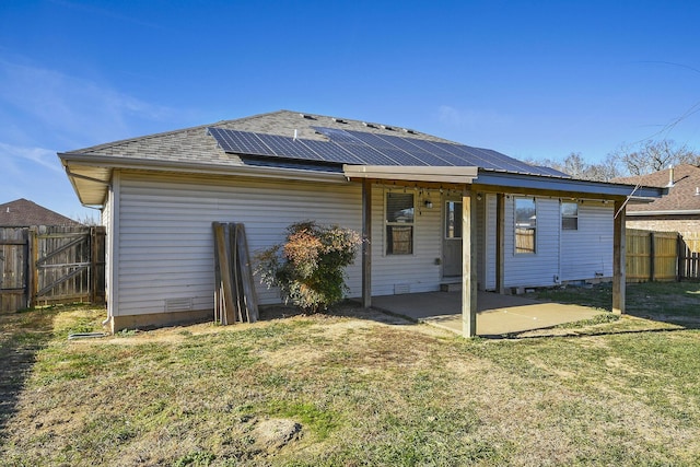 back of house with a patio area, a yard, and solar panels