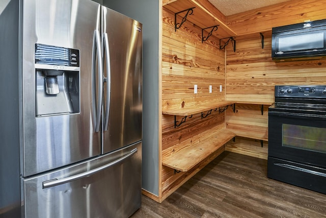 kitchen with a textured ceiling, wooden walls, black appliances, and dark hardwood / wood-style floors