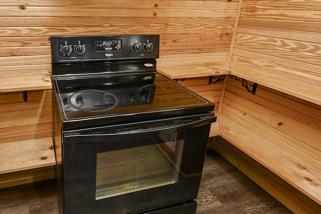 interior space with black range with electric cooktop, dark hardwood / wood-style floors, and wood walls