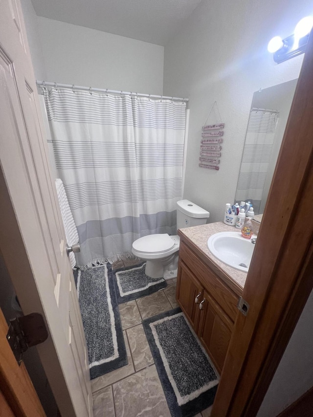 bathroom featuring tile patterned flooring, vanity, walk in shower, and toilet