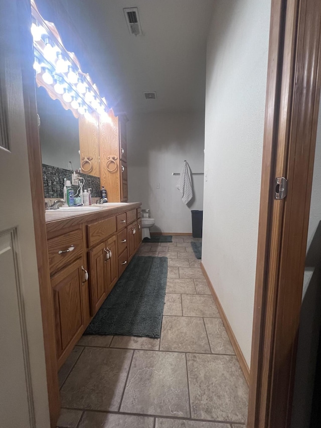 bathroom featuring vanity, toilet, and decorative backsplash