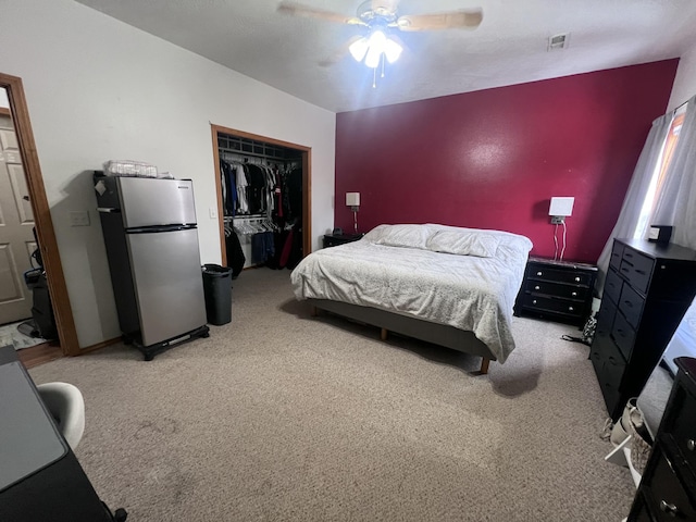 carpeted bedroom with ceiling fan, stainless steel fridge, and a closet