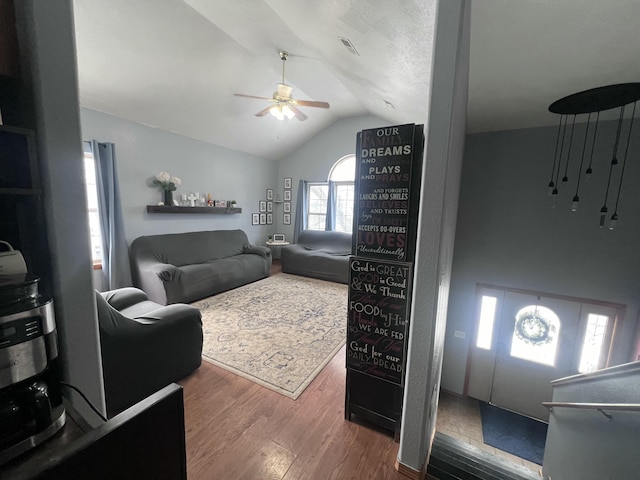 living room with dark hardwood / wood-style flooring, lofted ceiling, and ceiling fan