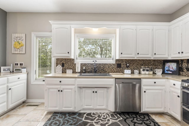 kitchen with stainless steel dishwasher, a healthy amount of sunlight, white cabinetry, and sink