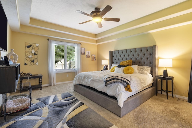 bedroom featuring a tray ceiling, ceiling fan, and light colored carpet