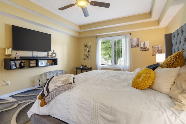 carpeted bedroom featuring a tray ceiling and ceiling fan