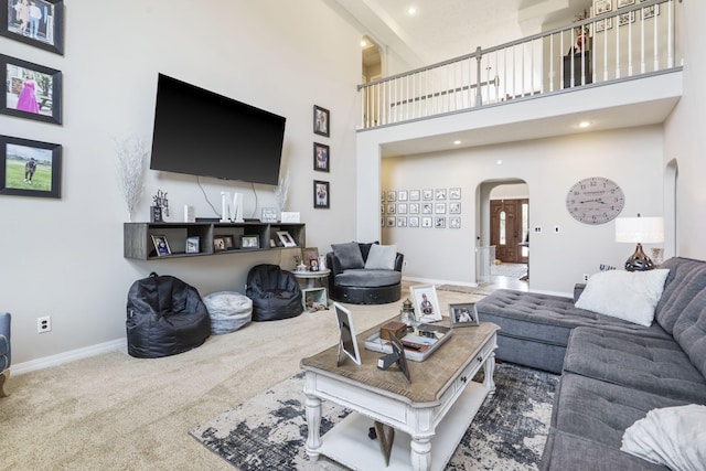 carpeted living room featuring a towering ceiling