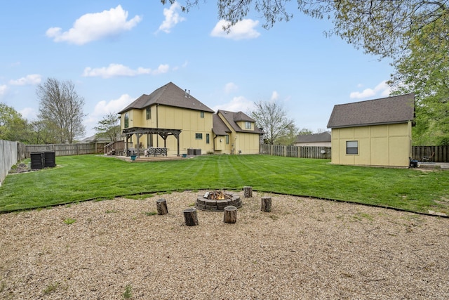 back of property with a fenced backyard, a lawn, and an outdoor fire pit