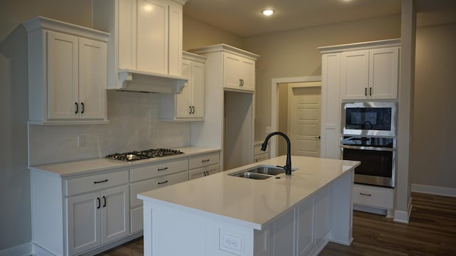 kitchen with white cabinetry, sink, stainless steel appliances, backsplash, and a kitchen island with sink